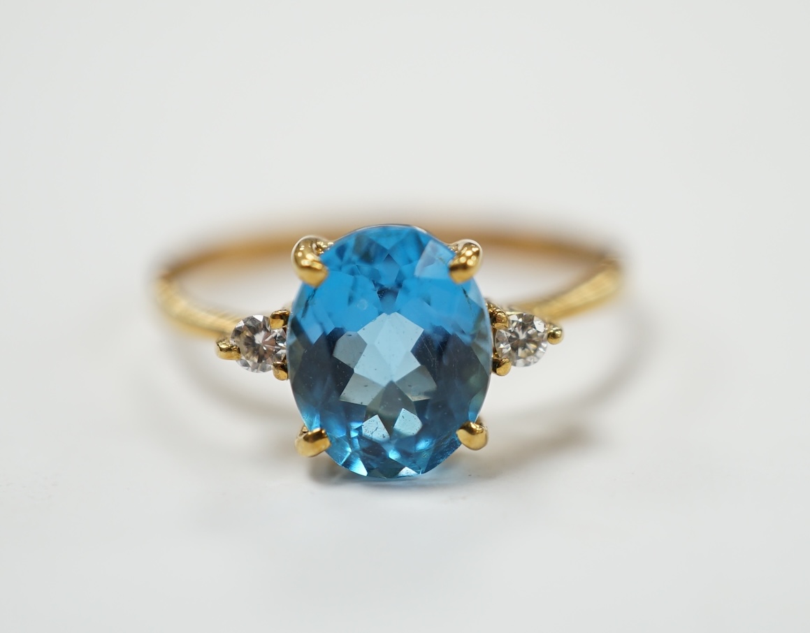 A 750 yellow metal and single stone oval cut blue topaz and two stone diamond set ring, size M/N, gross weight 2.5 grams. Good condition.